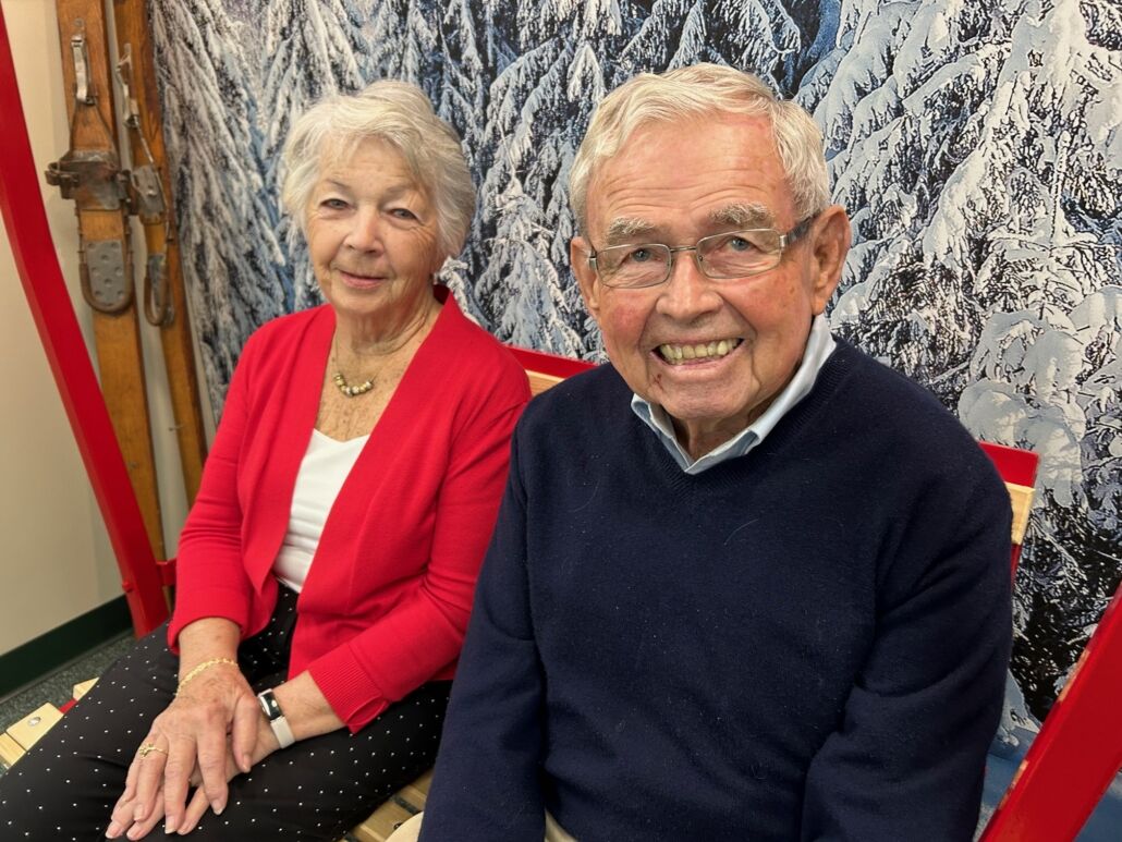 Bud Heck, founder of Alpenhaus, seated in front of a snowy forest mural with vintage skis