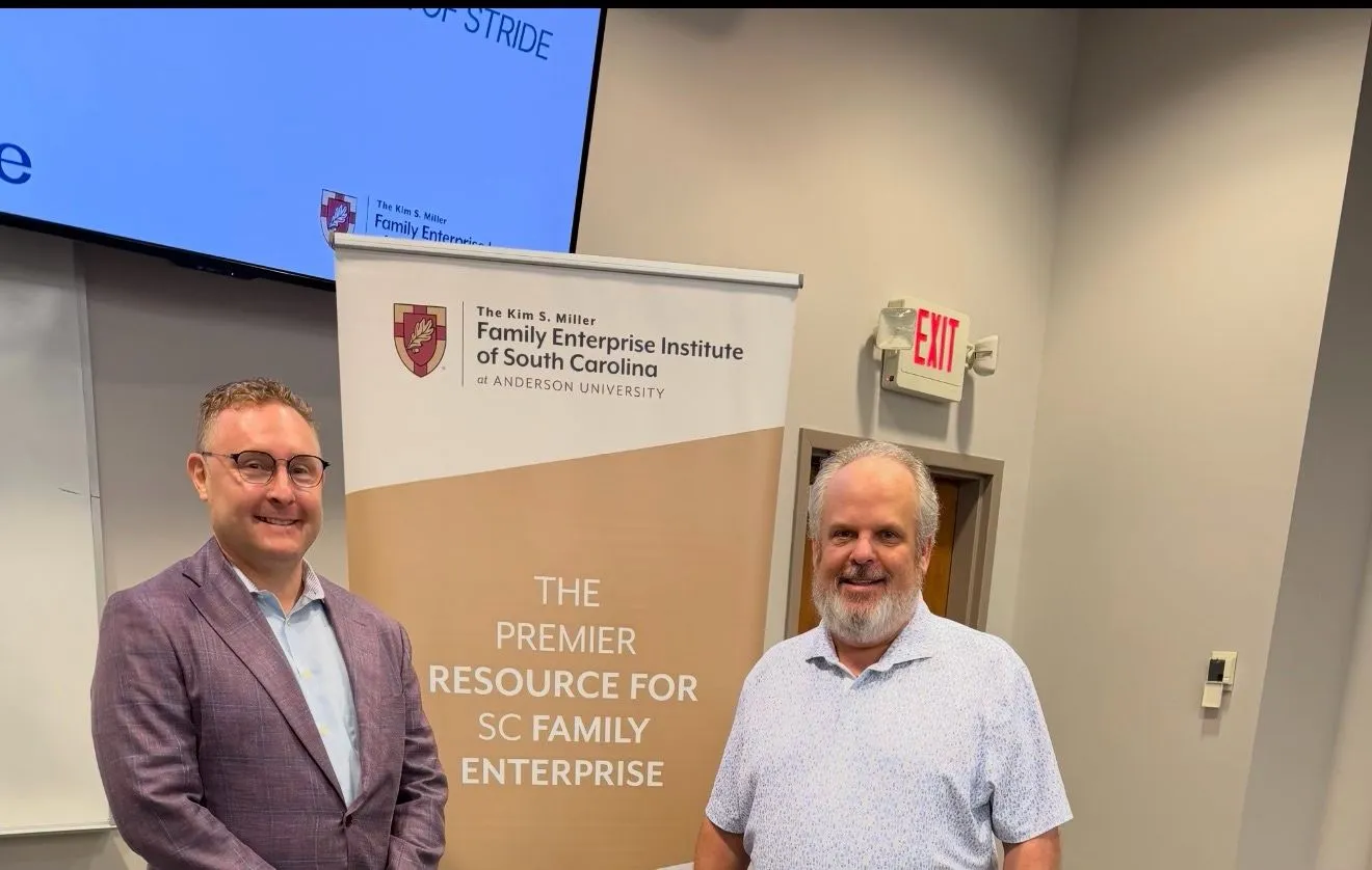 Jason Packer and Dr. Brad Bechtold beside the Kim S. Miller Family Enterprise Institute of South Carolina banner